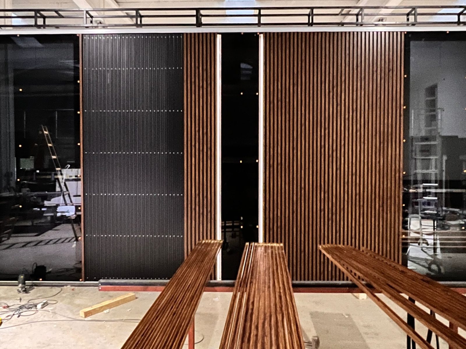 Entry wall of wood-look slats and black panels with lit vertical reveals