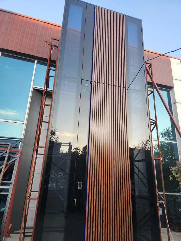 Two-story entry of tall black glass panels and a wood-look slat column