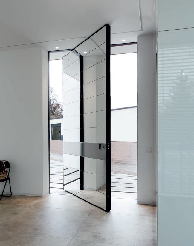 Floor-to-ceiling mirror-glass pivot door with a brushed steel band, open beside tall glass sidelites