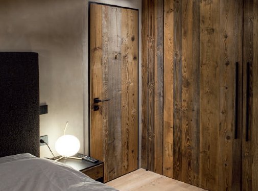 Reclaimed-wood flush interior door in a matching reclaimed-wood bedroom wall