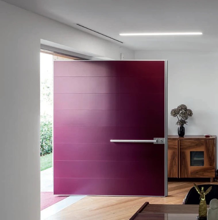 Wide plum-colored pivot door with horizontal grooves and a long steel pull, open to the patio