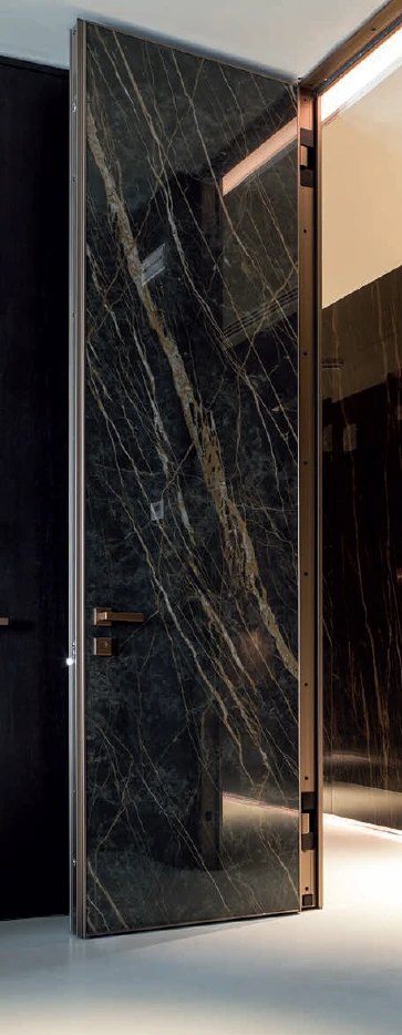 Tall black marble interior door with bronze hardware and frame