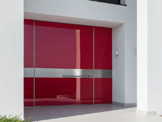 Gloss red glass pivot entry wall with a full-width brushed steel band and horizontal pull