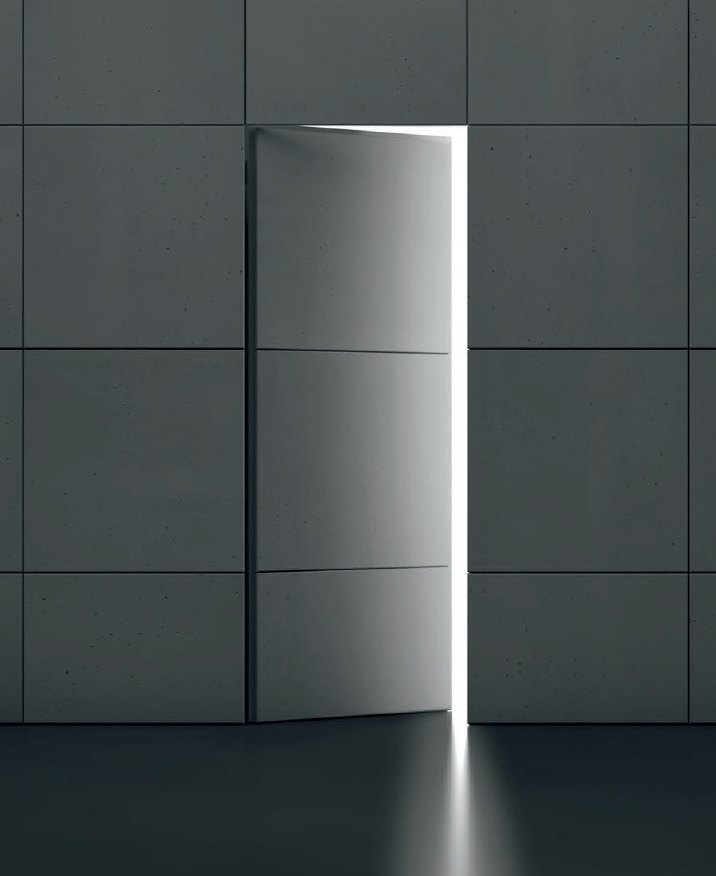 Concealed flush door in a concrete-panel wall, open with light spilling through the gap
